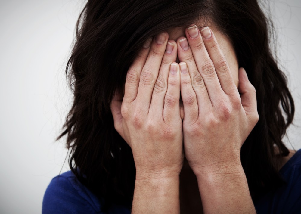 Why women suffer from anxiety. Anxious woman with her face buried in her hands.